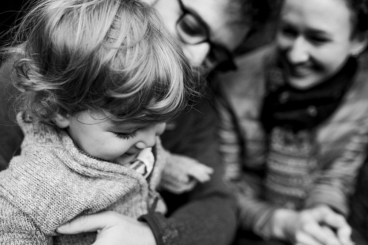 nyc family and newborn photographer mom and dad sit with toddler on parks steps in outdoor winter family session