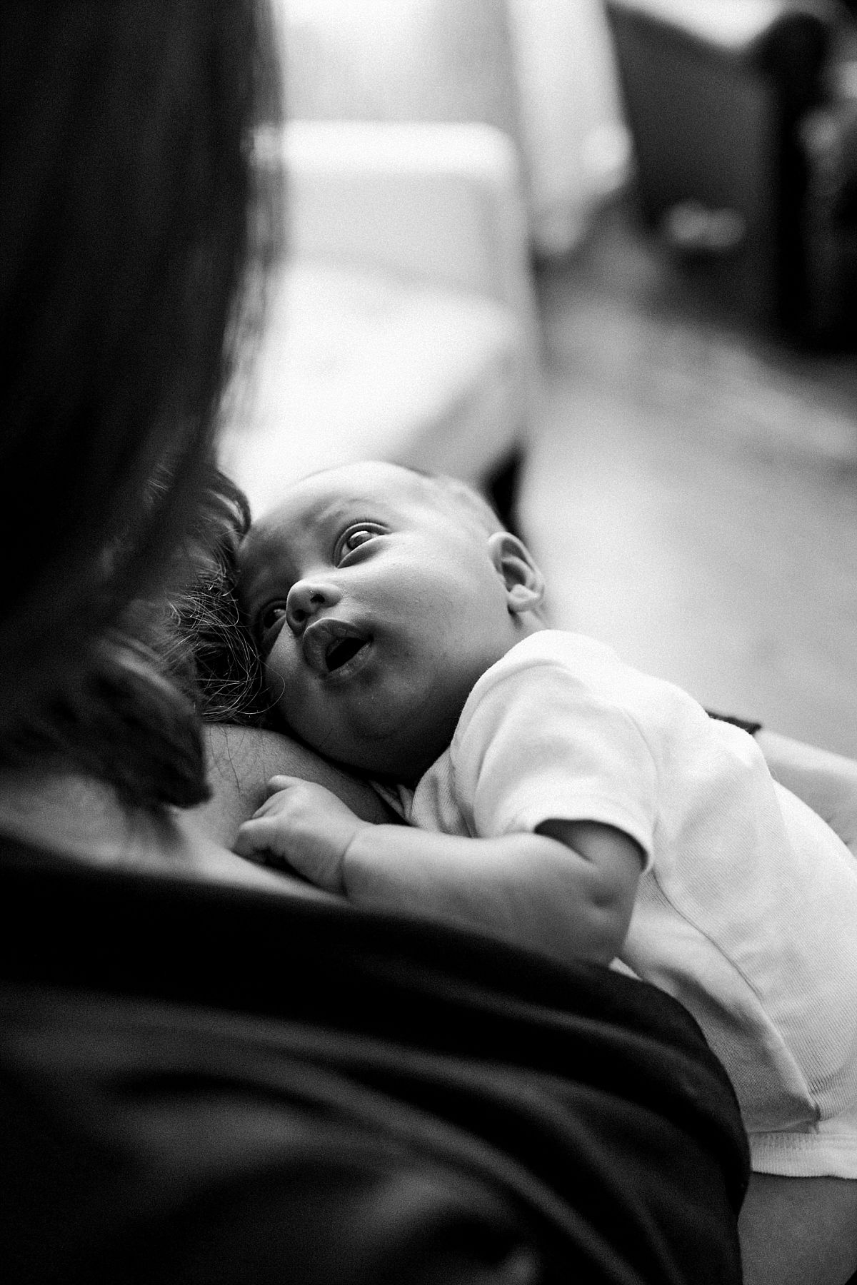 nyc family and newborn photographer gorgeous baby likes in mom's arms and looks up lovingly