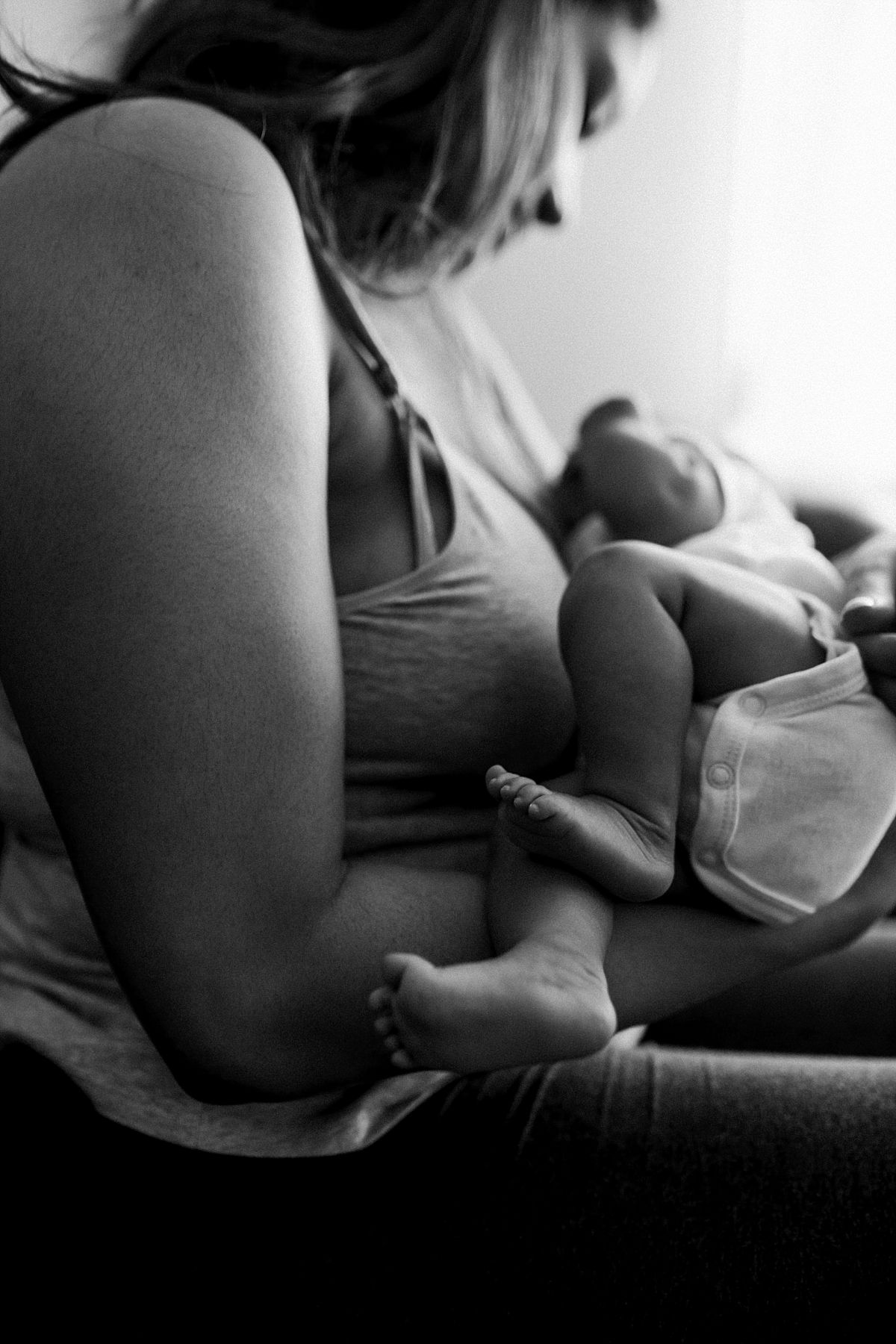 nyc family and newborn photographer mom holds newborn baby girl across chest and baby feet dangle in mommy and me session