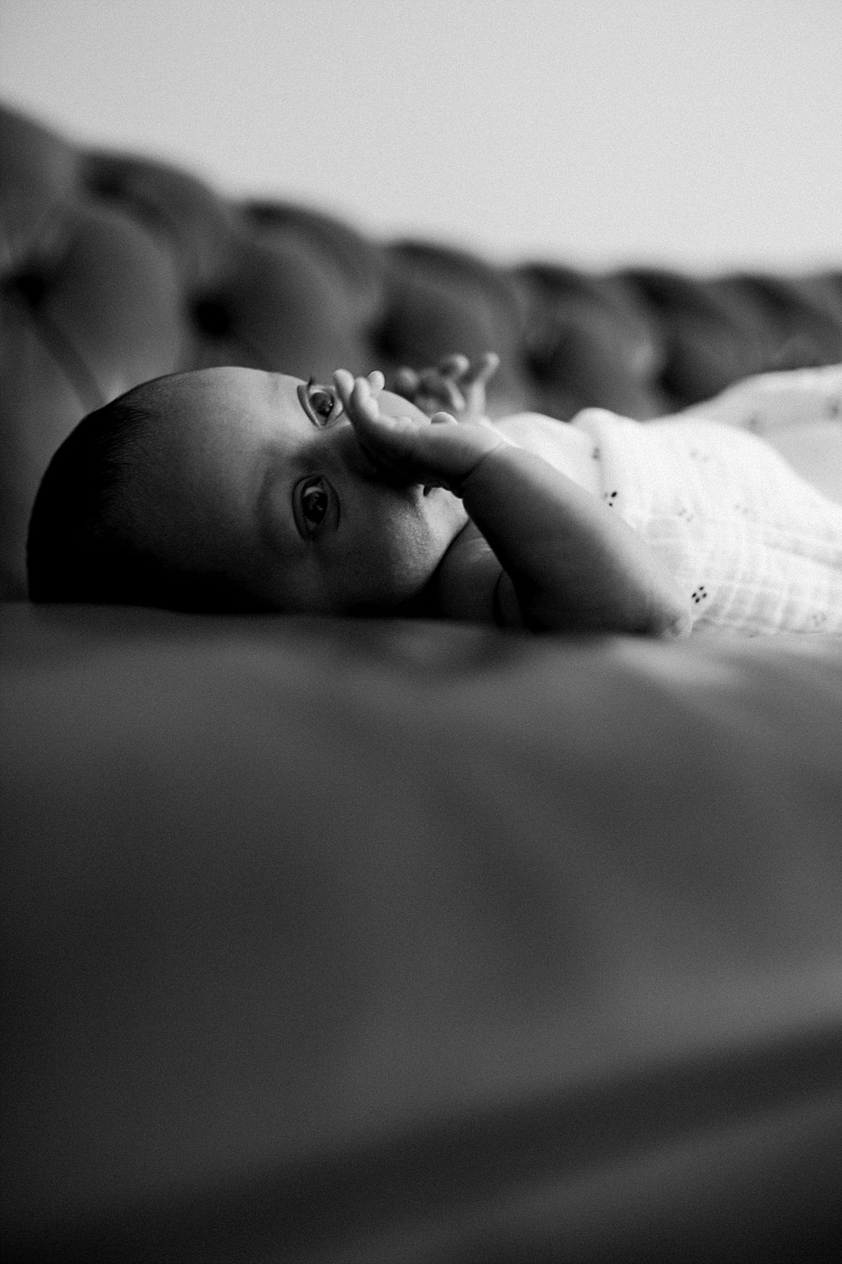 nyc family and newborn photographer newborn girl lies on couch and stetches arms out at in home session