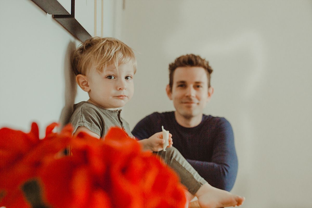 nyc family and newborn photographer dad sits with son eating cheese at in home family session in nyc