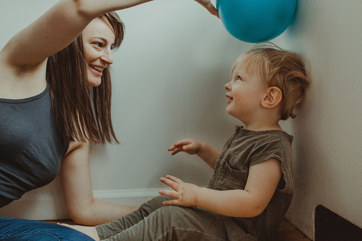 nyc family and newborn photographer mom and son play with ball in parents room in manhattan