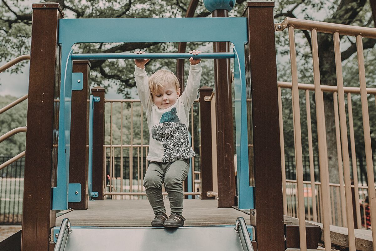 nyc family and newborn photographer boy plays with slide at nyc playground