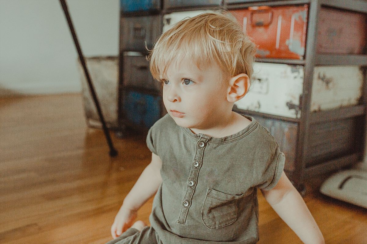 nyc family and newborn photographer boy sits in front of industrial chester drawers in bedroom