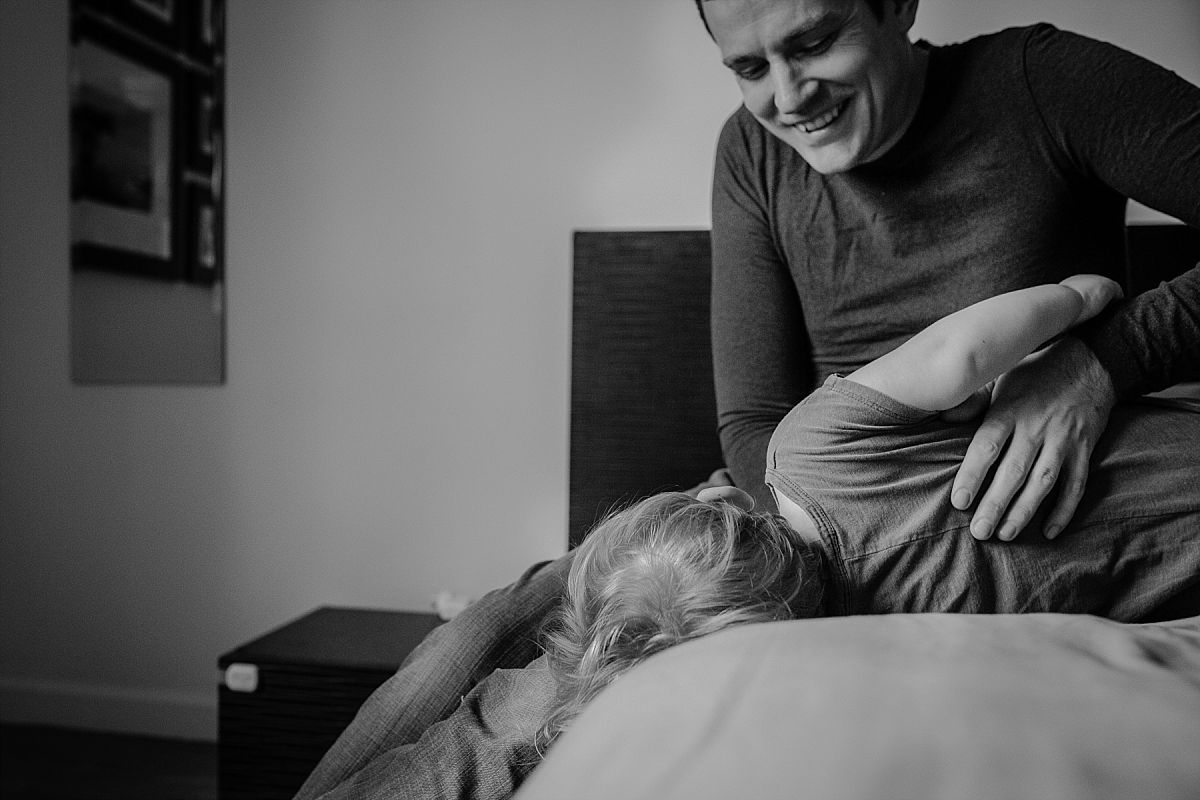 nyc family and newborn photographer dad tickles son for big laughter in nyc in home session