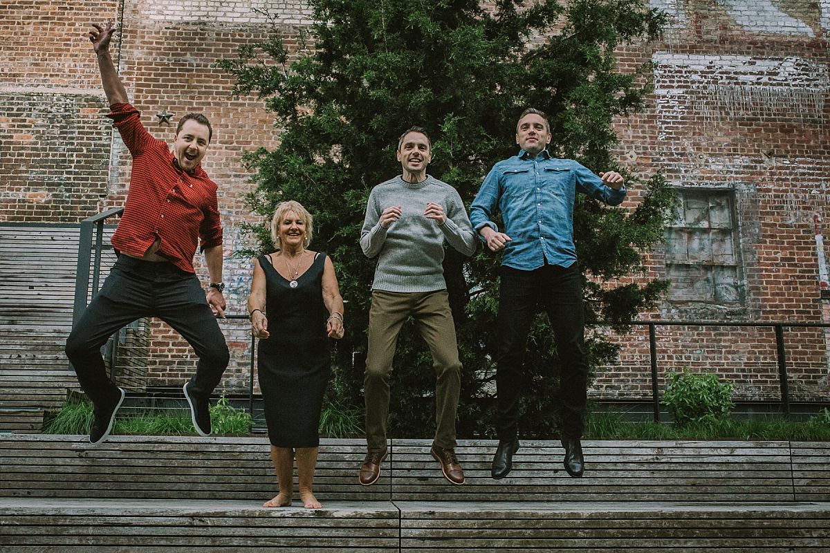 mom and three sons in the air jumping off park bench during lifestyle family photo session in nyc
