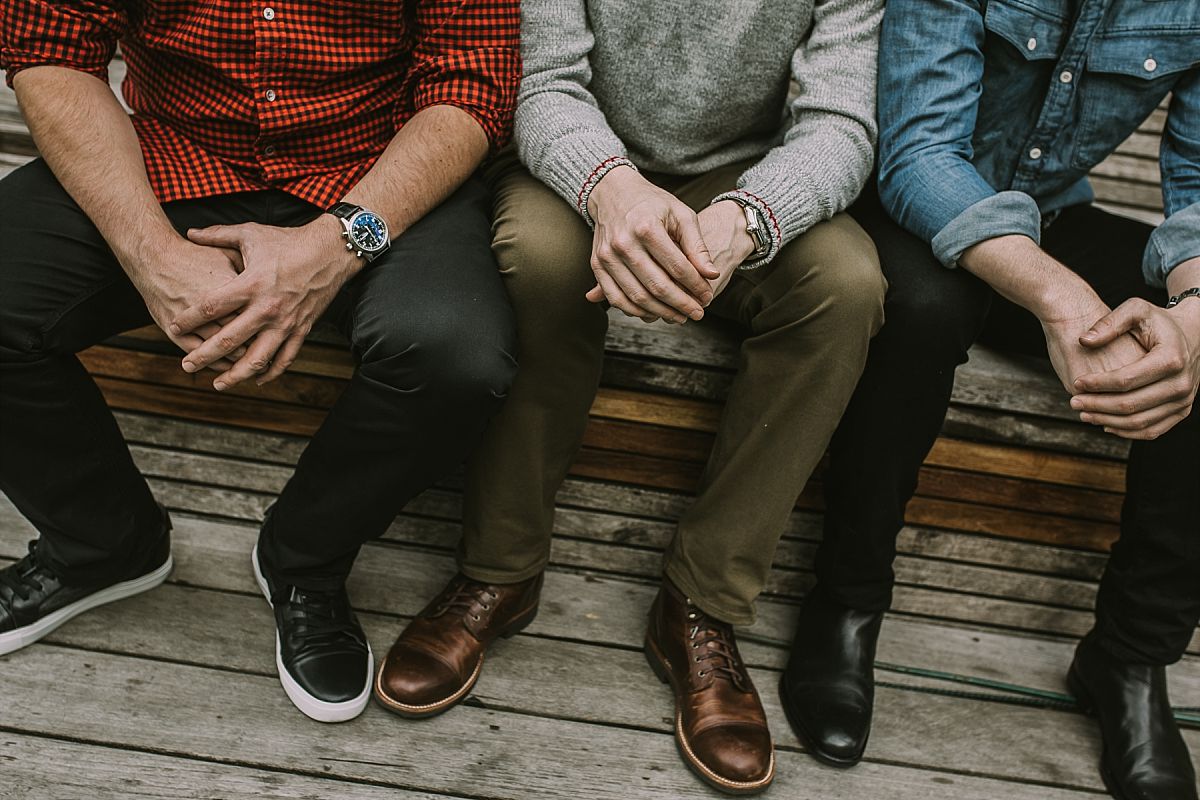 detail shot of three sons sitting at a park with hands overlapping in during lifestyle family photo session in nyc. Krystil McDowall photography