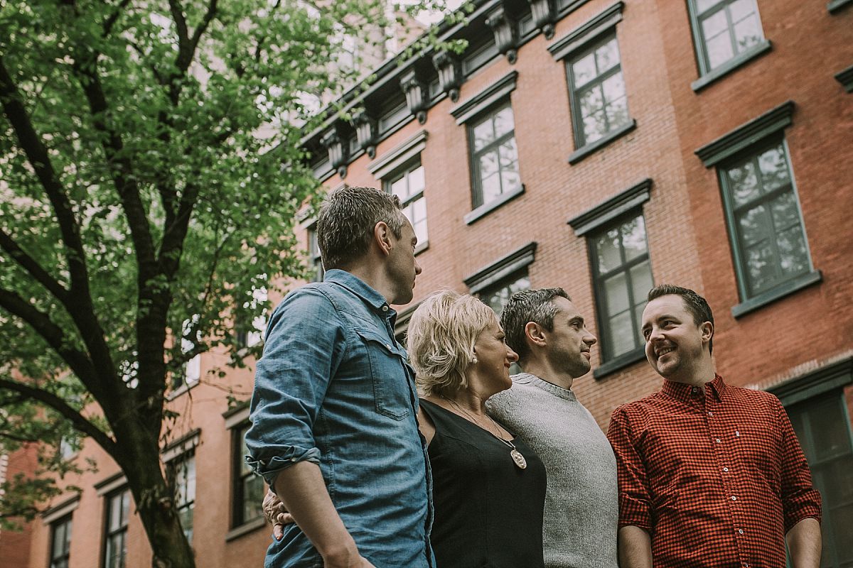mom and three sons in front of beautiful brownstones in chelsea manhattan for nyc family photo session. image by Krystil McDowall Photography