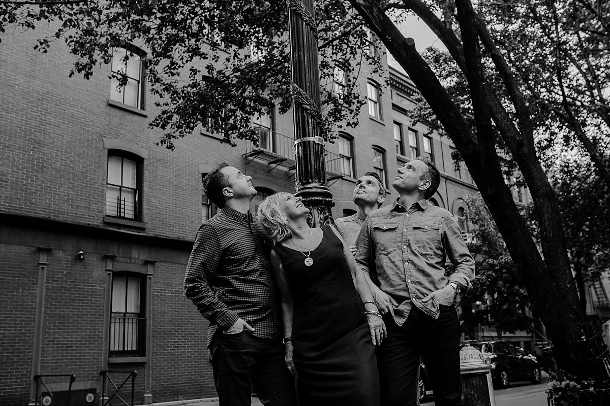 mom and three sons looking up at street sign in chelsea during nyc family photo session. photo by krystil mcdowall photography