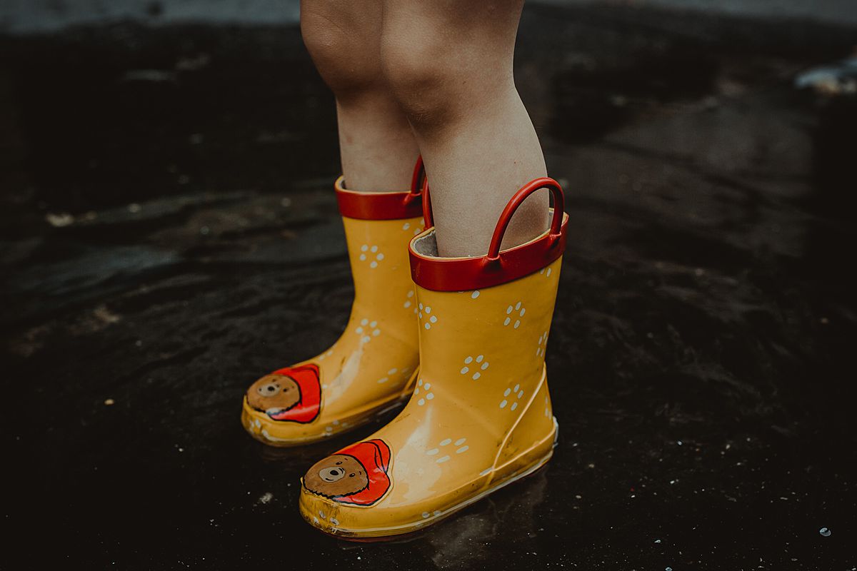 daughter's yellow rainboots that have paddington bear. photo taken while toddler stands in puddle