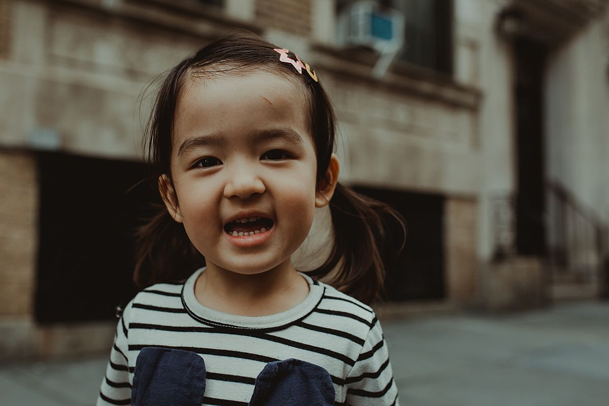 portrait of daughter smiling in pale blue dress with a cat on nyc sidewalk 