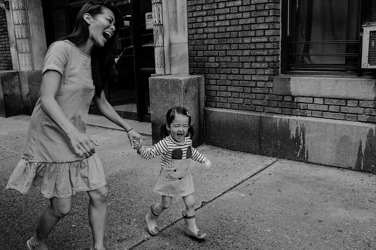 mom and daughter walk along nyc streets of Manhattan laughing heaps and holding hands. nyc family and newborn photographer. photo by krystil mcdowall