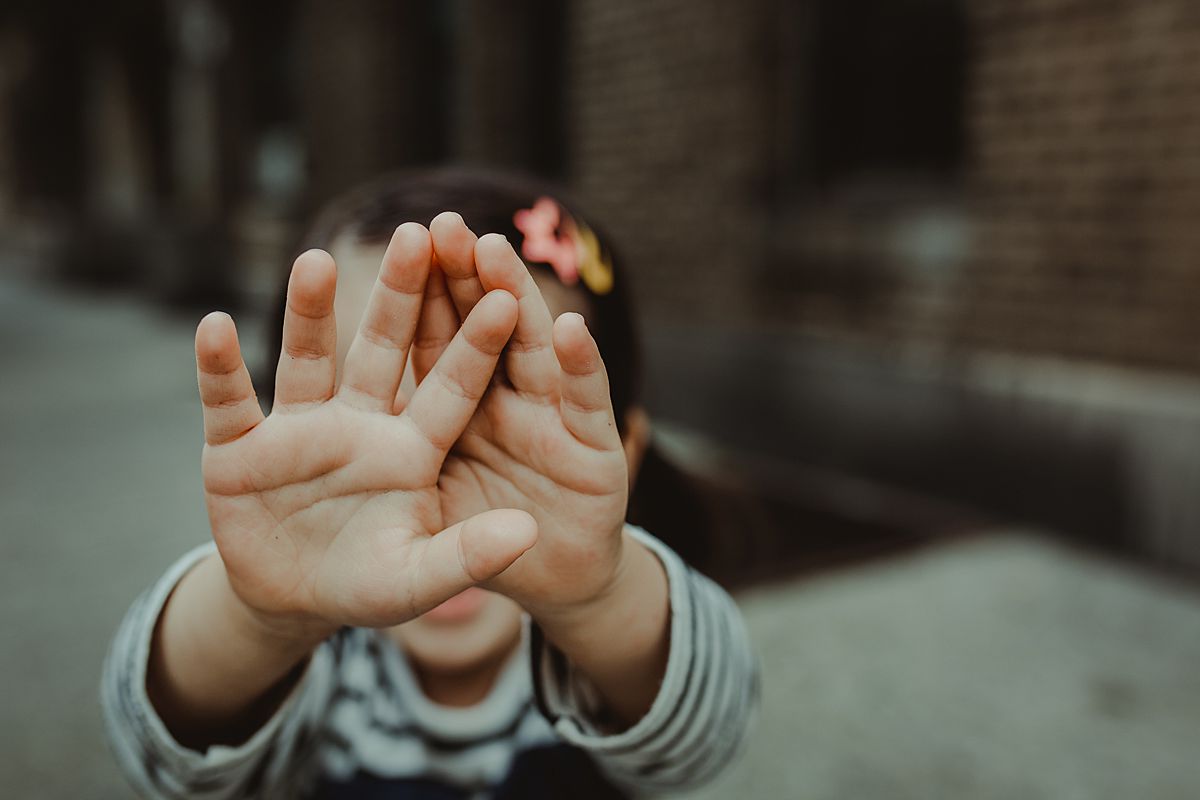 daughter holds hands over her face shying away from the camera during documentary lifestyle session by nyc family and newborn photographer krystil mcdowall