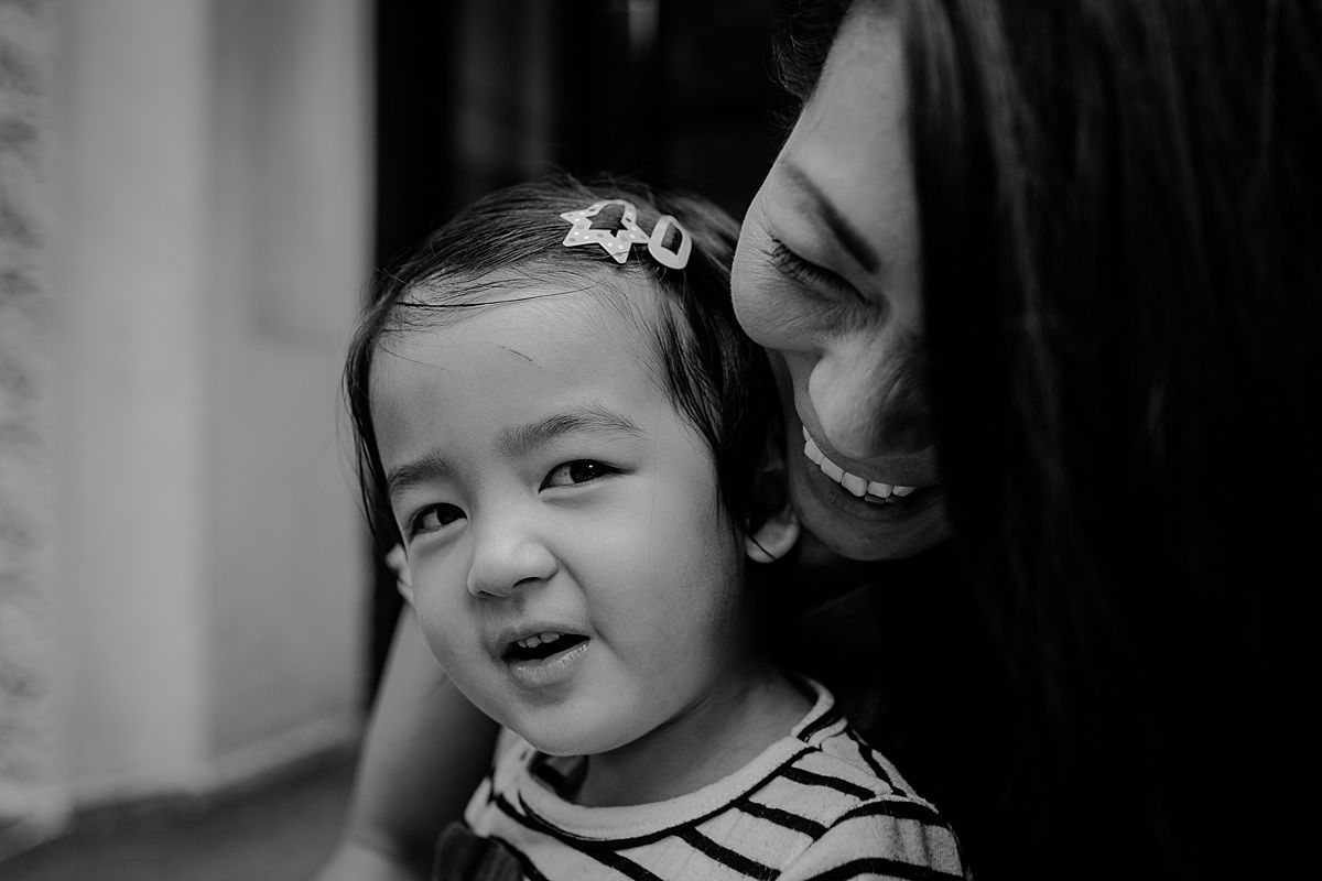 daughter sits on moms lap on nyc stoop in upper manhattan and mom has the hugest smile on her face. krystil mcdowall captures image in nyc documentary lifestyle session family and newborn photographer