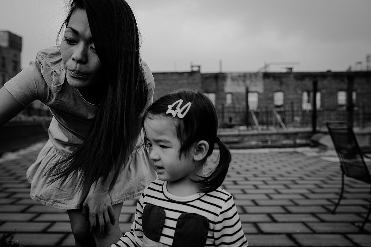 fun family photo shoot. mom and daughter discuss rooftop plants on sunny nyc afternoon outdoor session