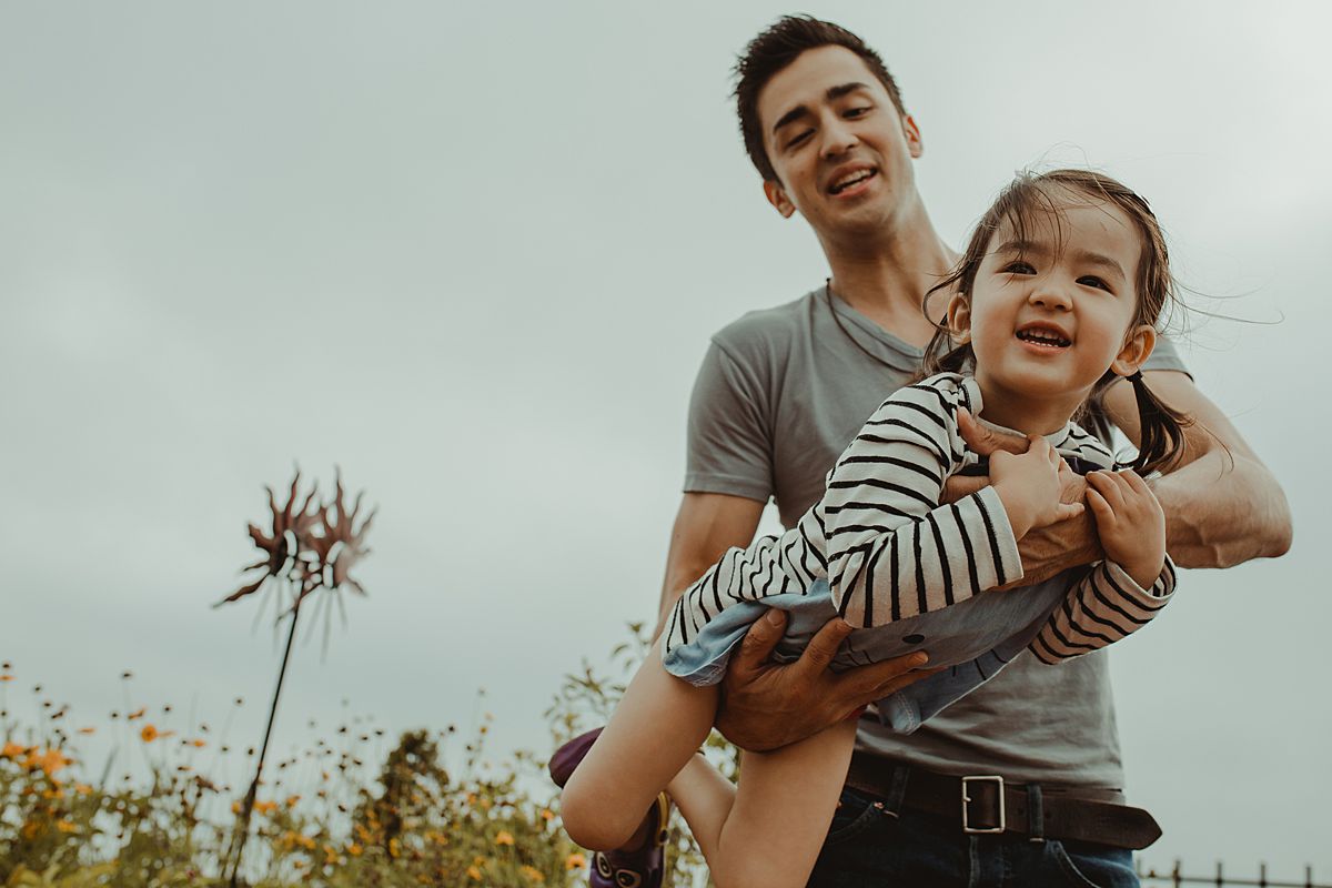 dad swings daughter around playfully and daughter is all her smiles. krystil mcdowall photography