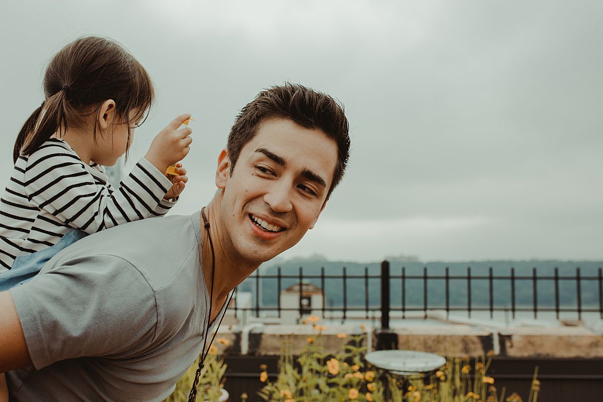 toddler enjoys piggy back from dad with dad laughing all the way. enjoying real life moments with families