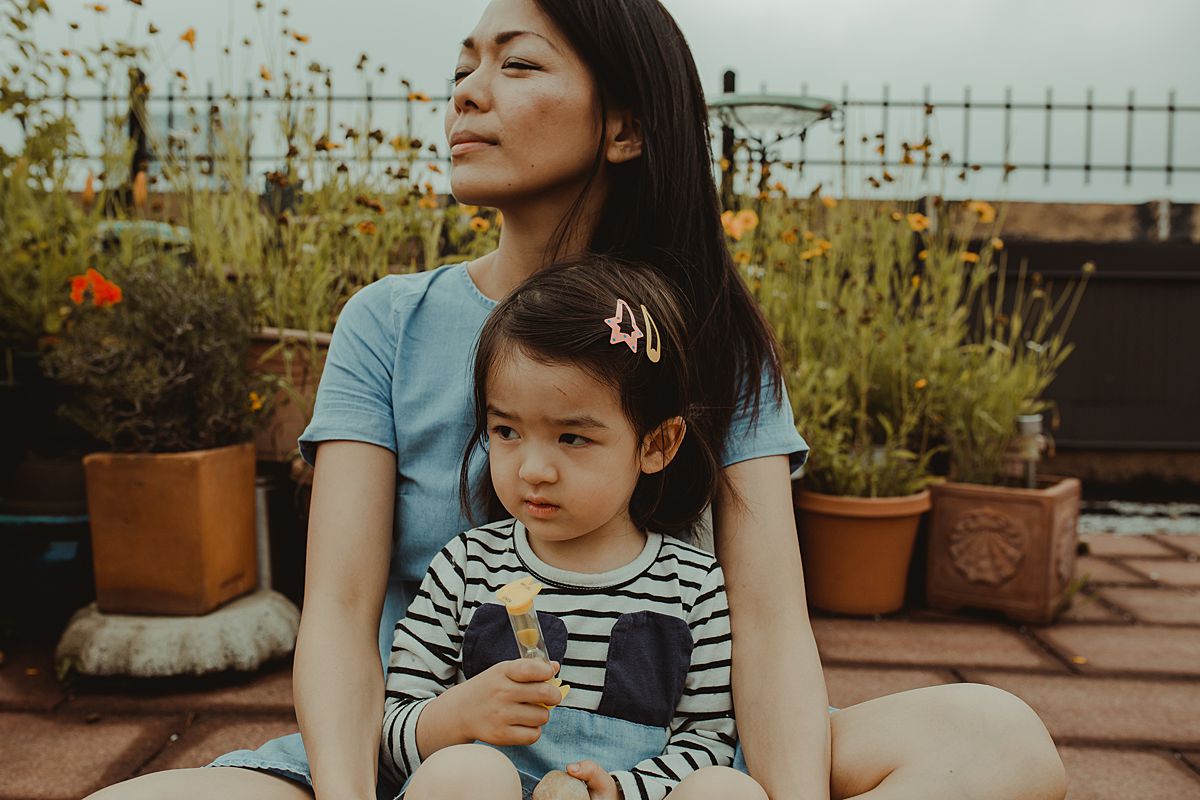 mom and daughter together on rooftop sitting by lovely potplants and enjoying the view