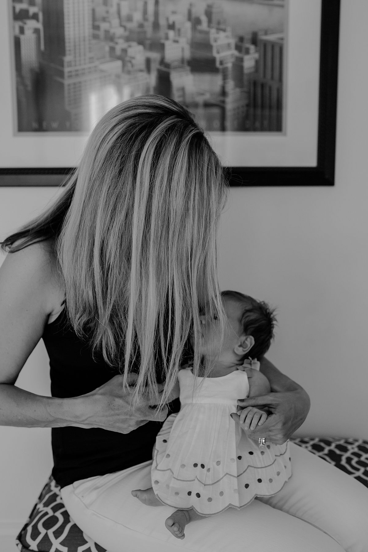 mom holding newborn baby girl sitting in front of nyc sign in family lifestyle session by nyc family and newborn photographer krystil mcdowall