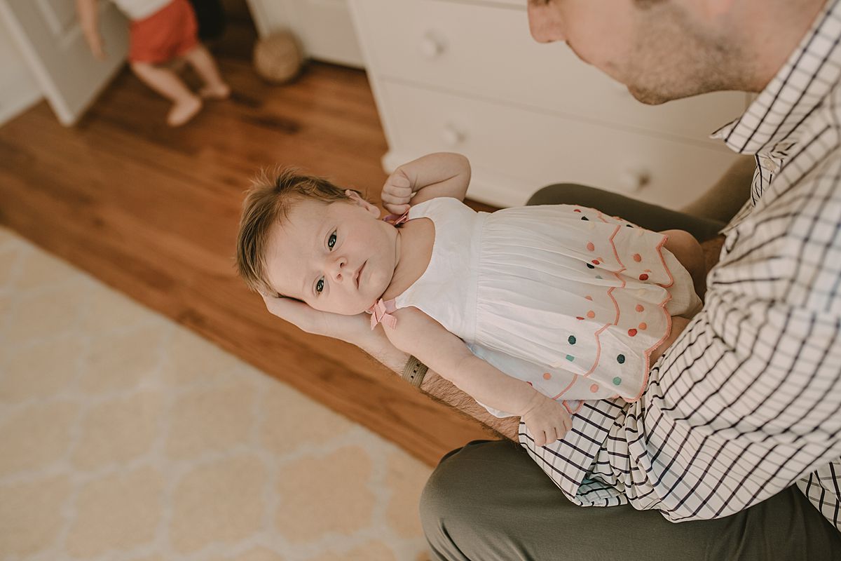 dad looking at newborn daughter as son runs into the room in nyc apartment
