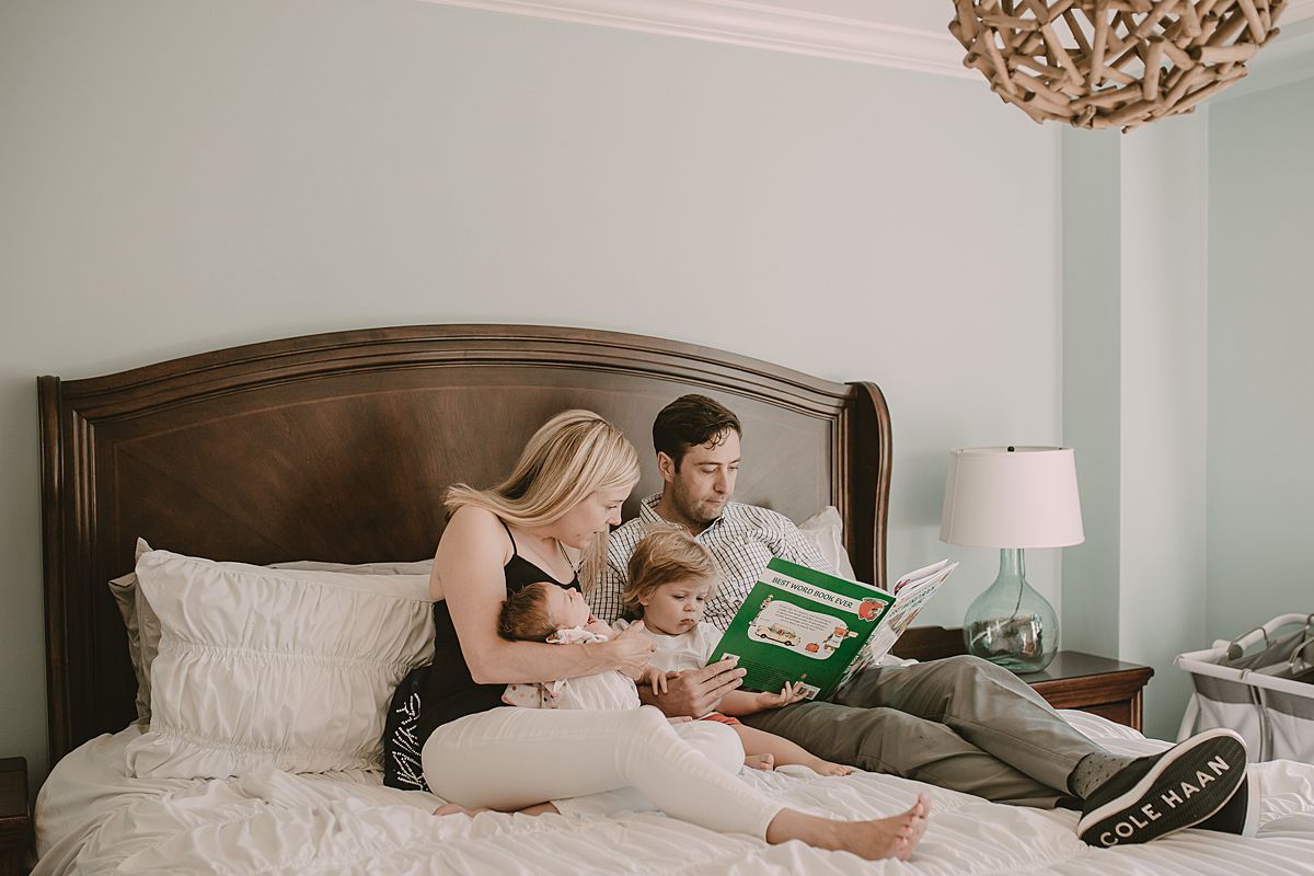 dad, mom, son and daughter reading stories on mom and dad's bed in nyc family lifestyle session