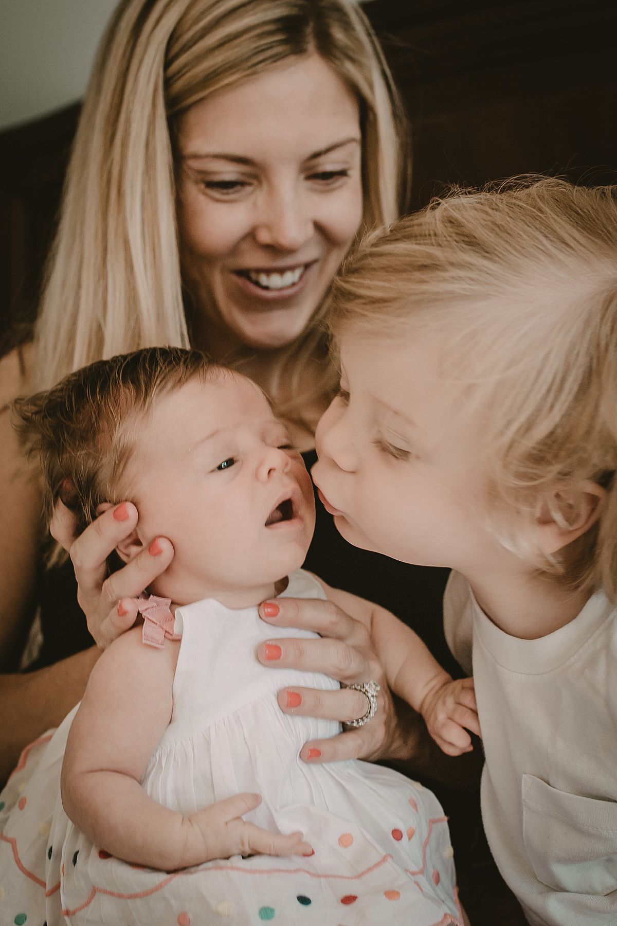 mom holding newborn baby girl while big brother tries to give little sister a kiss during nyc family documentary session