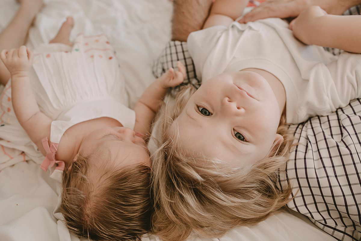 big brother and newborn sister lying on the bed with big brother looking at the camera. nyc newborn session. Image by nyc family and newborn photographer krystil mcdowall