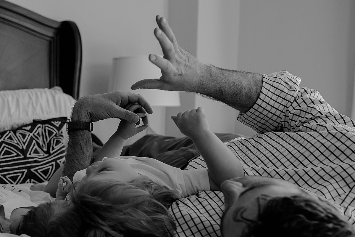 dad and son lying on the bed playing shdow puppets. documentary nyc newborn session by krystil mcdowall