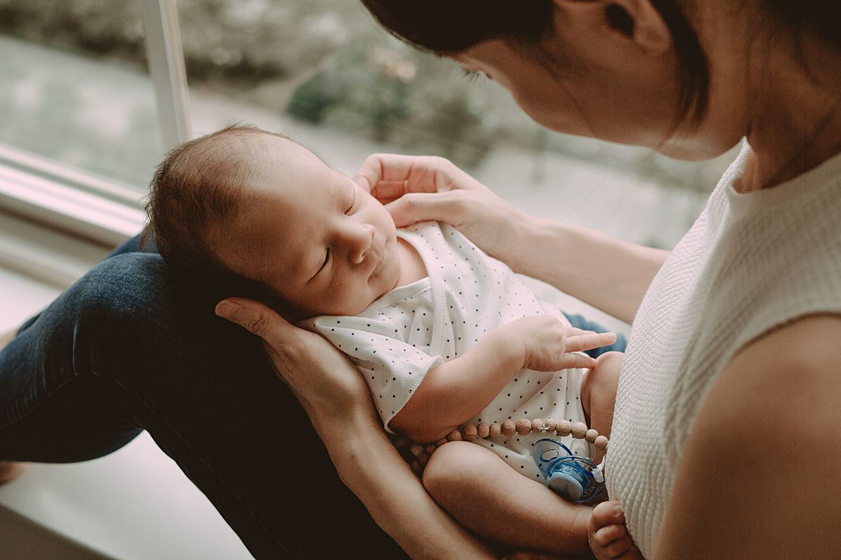 close up of mom holding newborn son in her lap and staring down lovingly at him