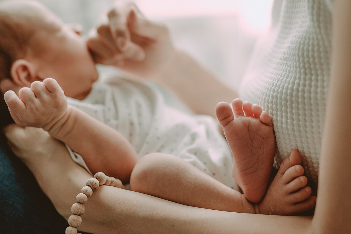 mom holds son on legs while mom looks over and touches son's face. image by nyc family and newborn photographers krystil mcdowall