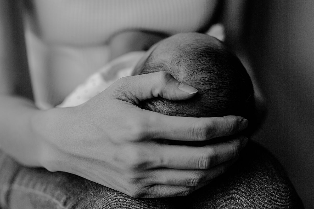 close up black and white image of mom's hand cupping her newborn's little head. image taken in downtown nyc apartment by krystil mcdowall photography