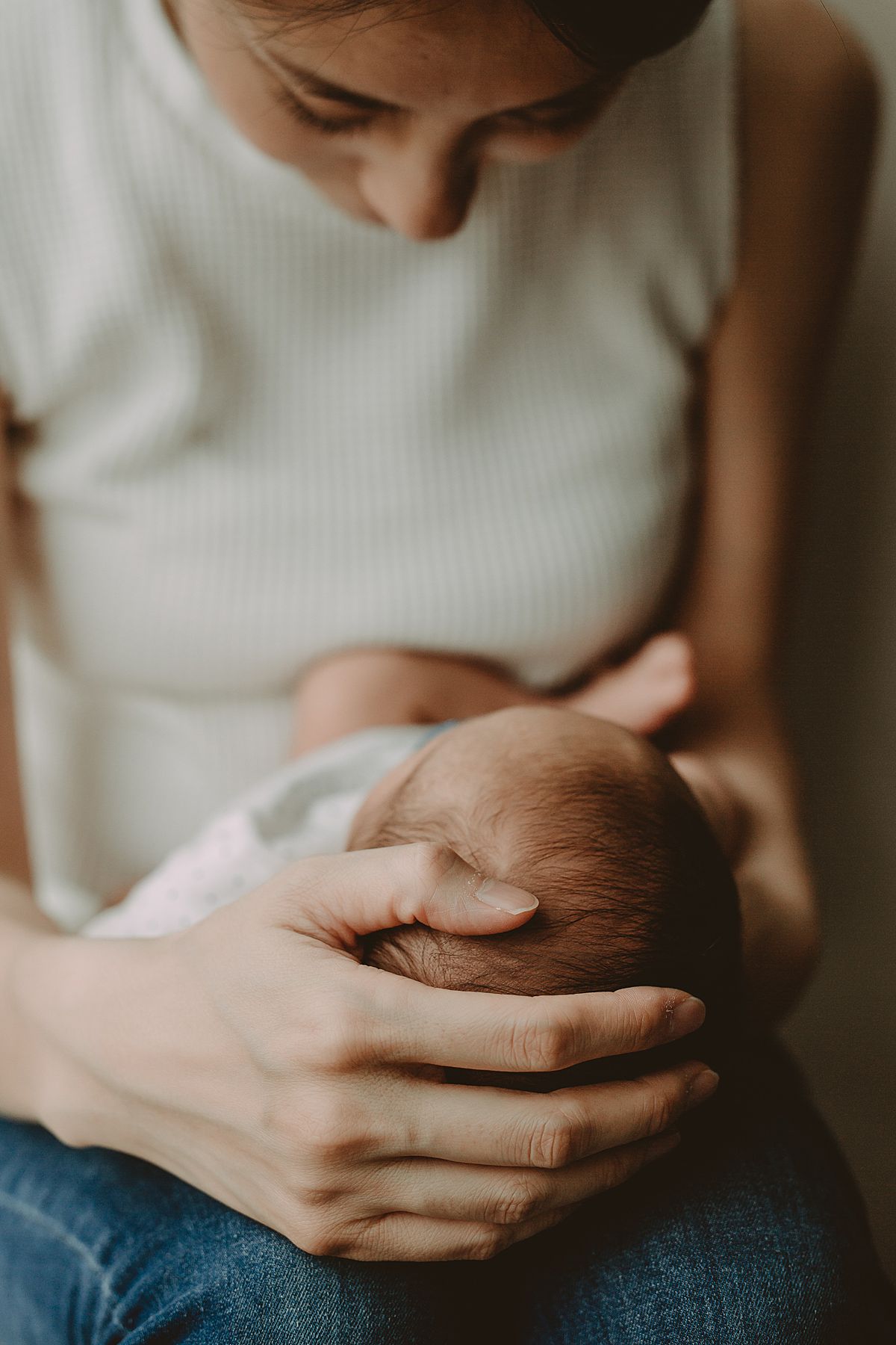 close up image of mom cupping her newborn's little head. image taken in downtown nyc apartment by krystil mcdowall photography
