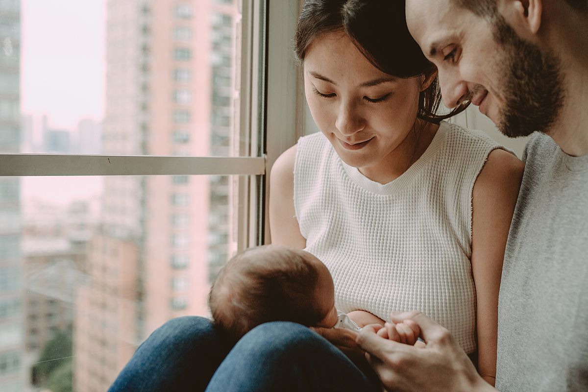 photo of mom, dad and newborn son all sitting in window sill during documentary family session in new york city