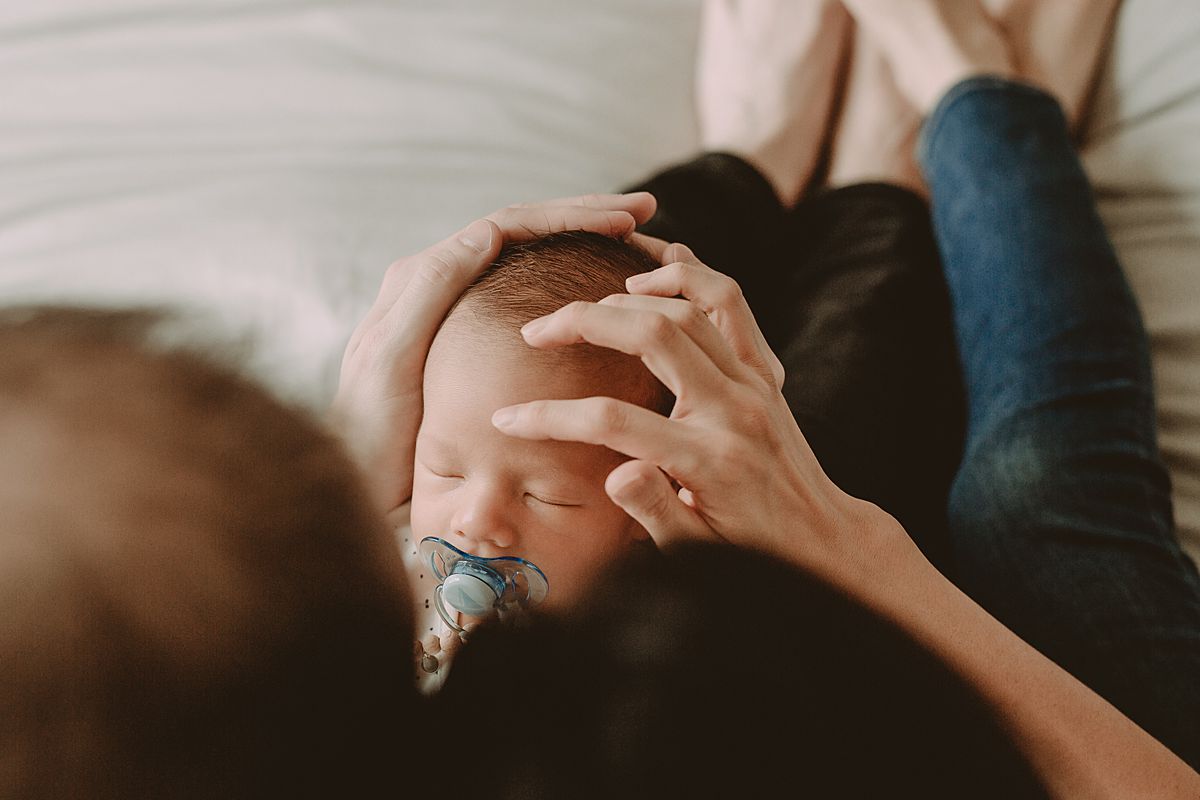 bird's eye view of mom and dad's heads and newborn son sleeping on dad's lap. enjoying real family moments in nyc