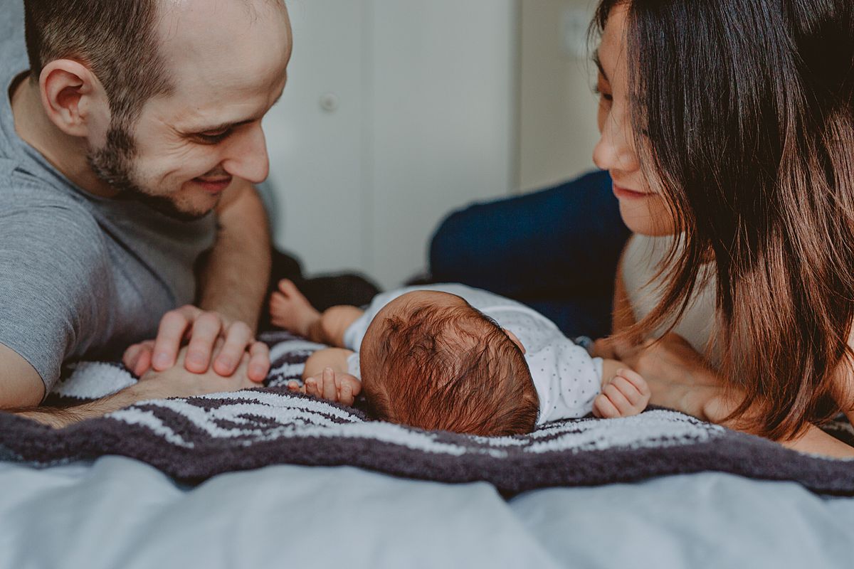 image of family laying on bed on black and white rug during nyc family lifestyle session. image by krystil mcdowall photography