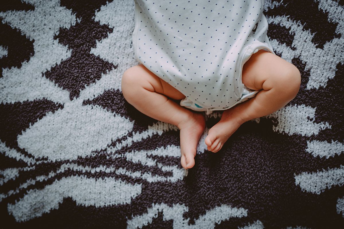 close up image of newborn's feet while laying on bed on black and white rug during nyc family lifestyle session. photo from krystil mcdowall photography
