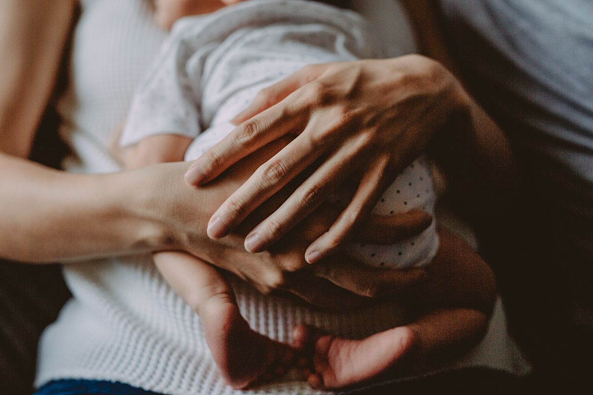 close up image of mom's hands cuddling tiny newborn body. image from krystil mcdowall
