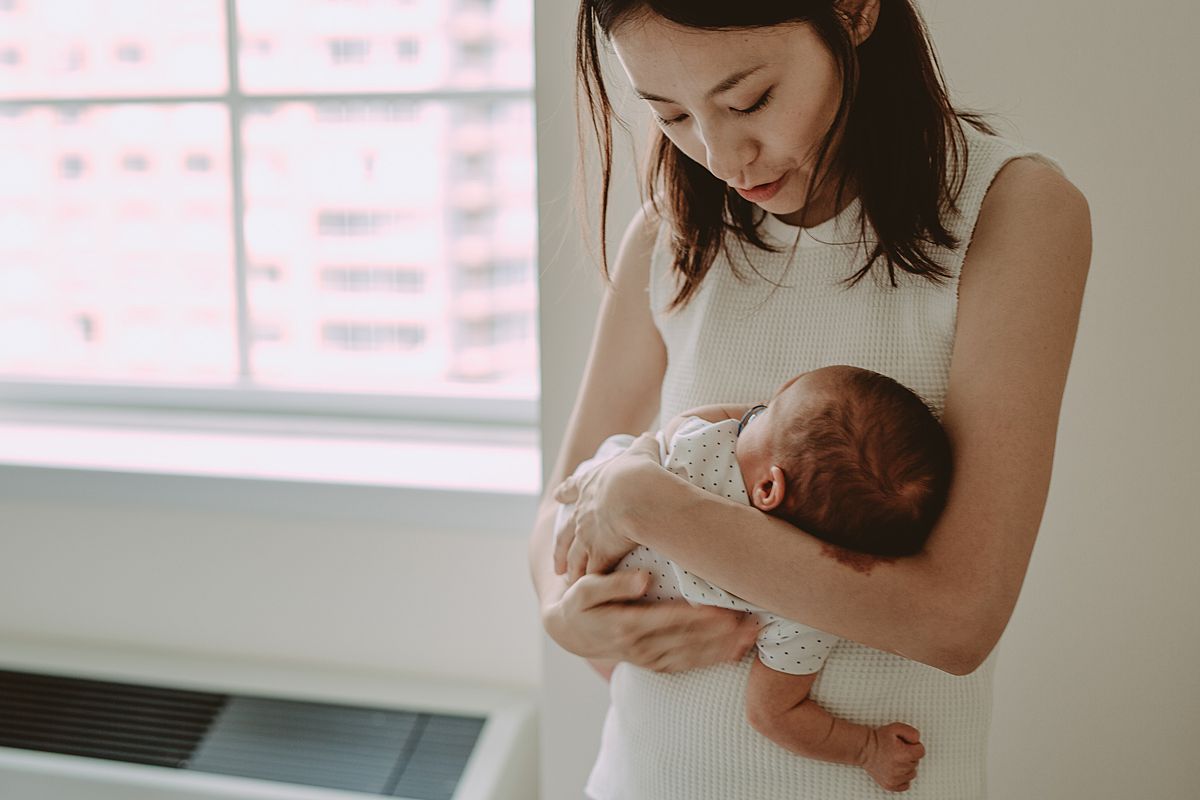 mom cuddling newborn son while he tries to sleep in nyc family lifestyle session. photo from krystil mcdowall