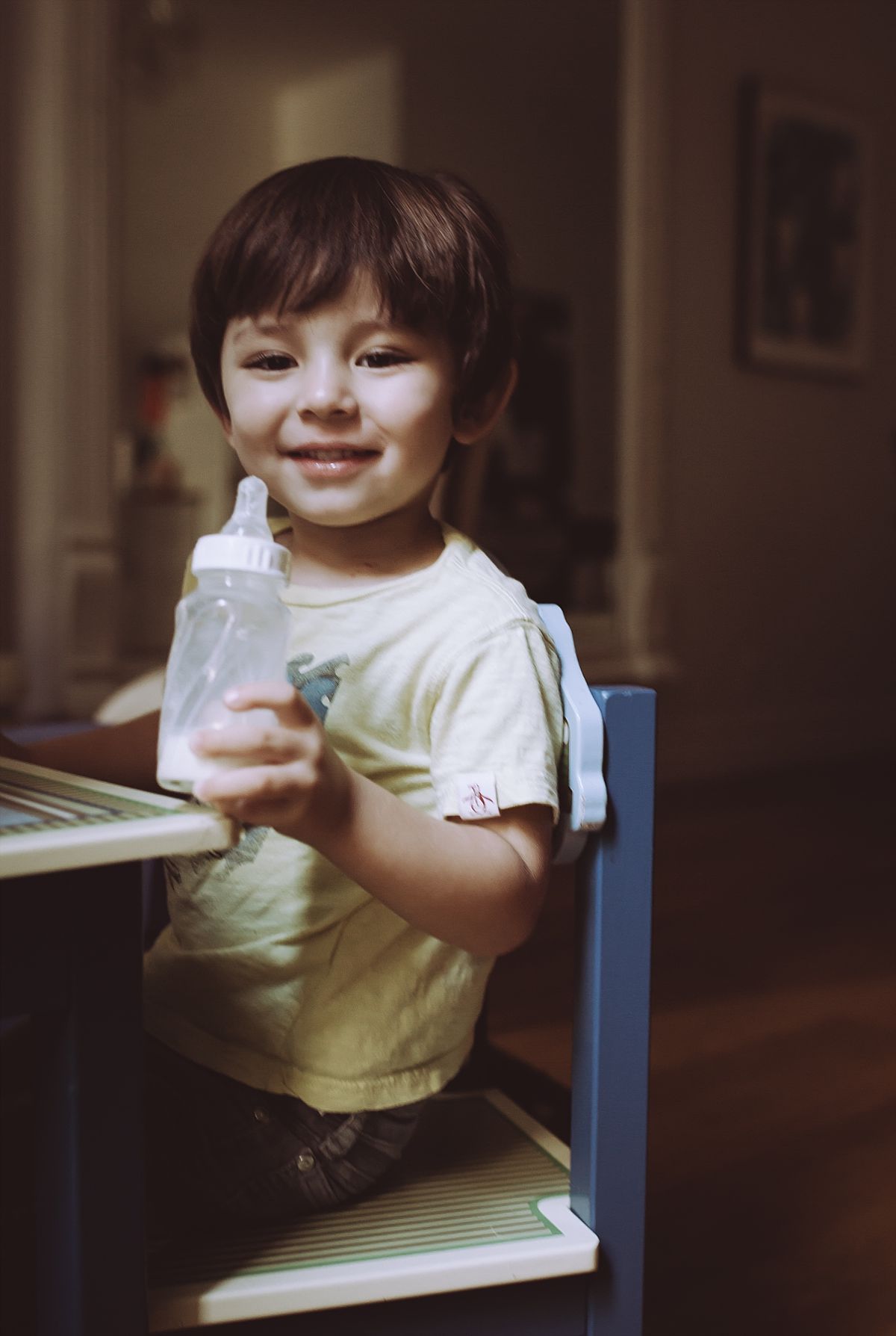portrait of boy sitting at the table drinking a bottle of milk. photo by nyc family and newborn photographer krystil mcdowall