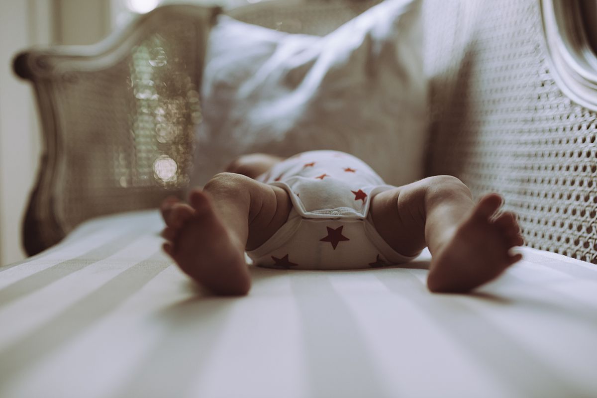 image of blurred baby feet while baby lies on bed. image by nyc family and newborn photographer krystil mcdowall