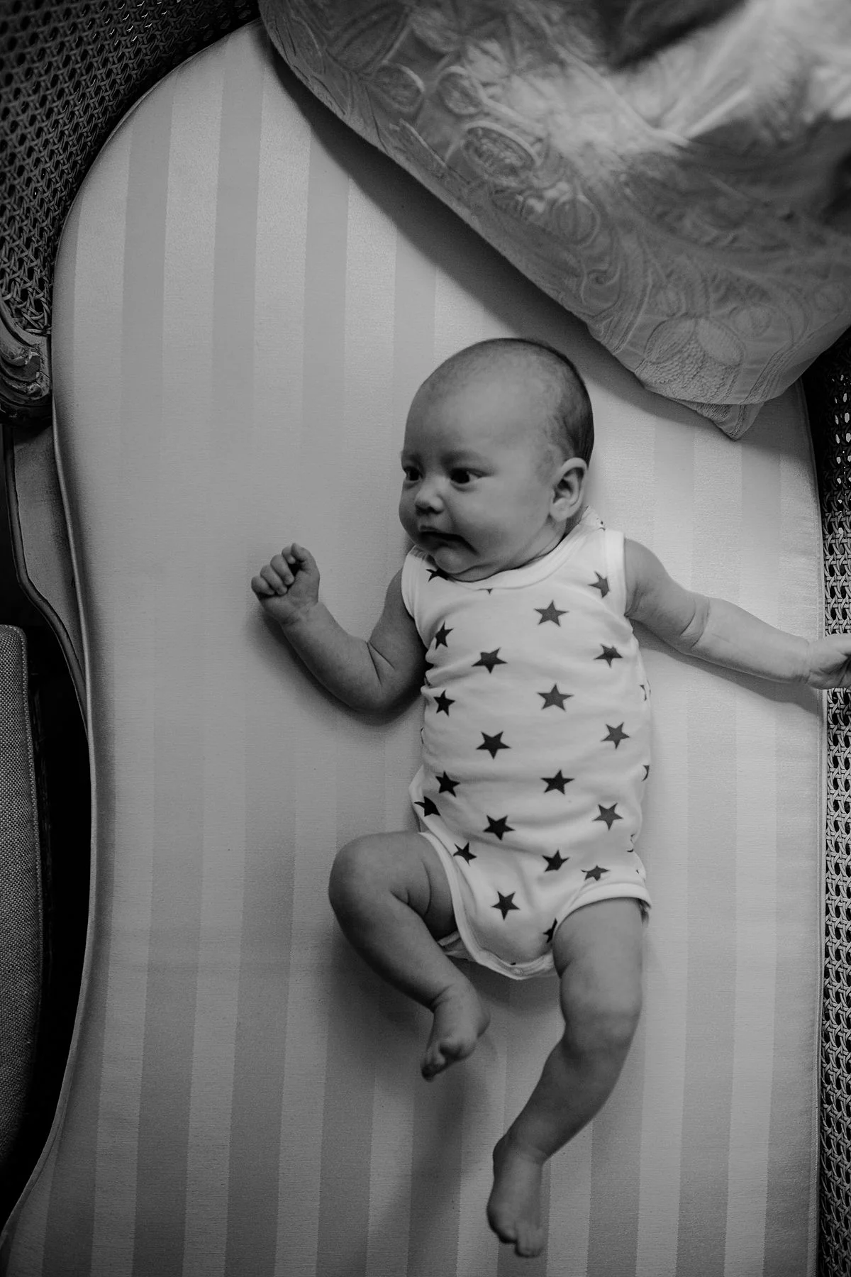 black and white image of newborn baby girl outstretched on family couch. image by krystil mcdowall photography