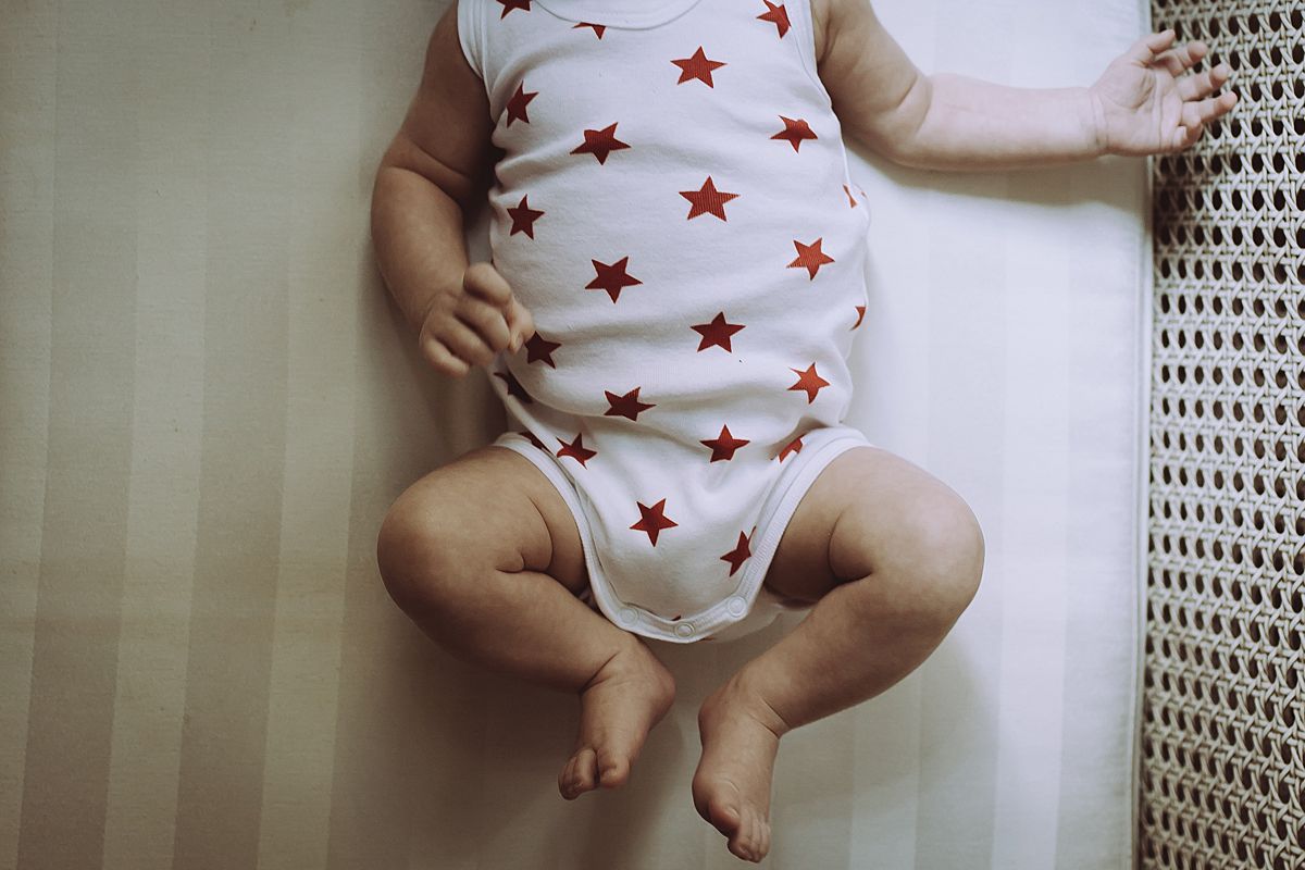 image of newborn baby girl in white and red star onesie. image by nyc family and newborn photographer krystil mcdowall