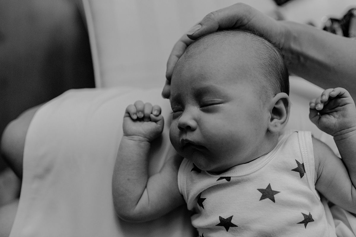 black and white image of newborn baby girl sleeping while mum cuddles her on family couch. image by nyc family and newborn photographer krystil mcdowall photography
