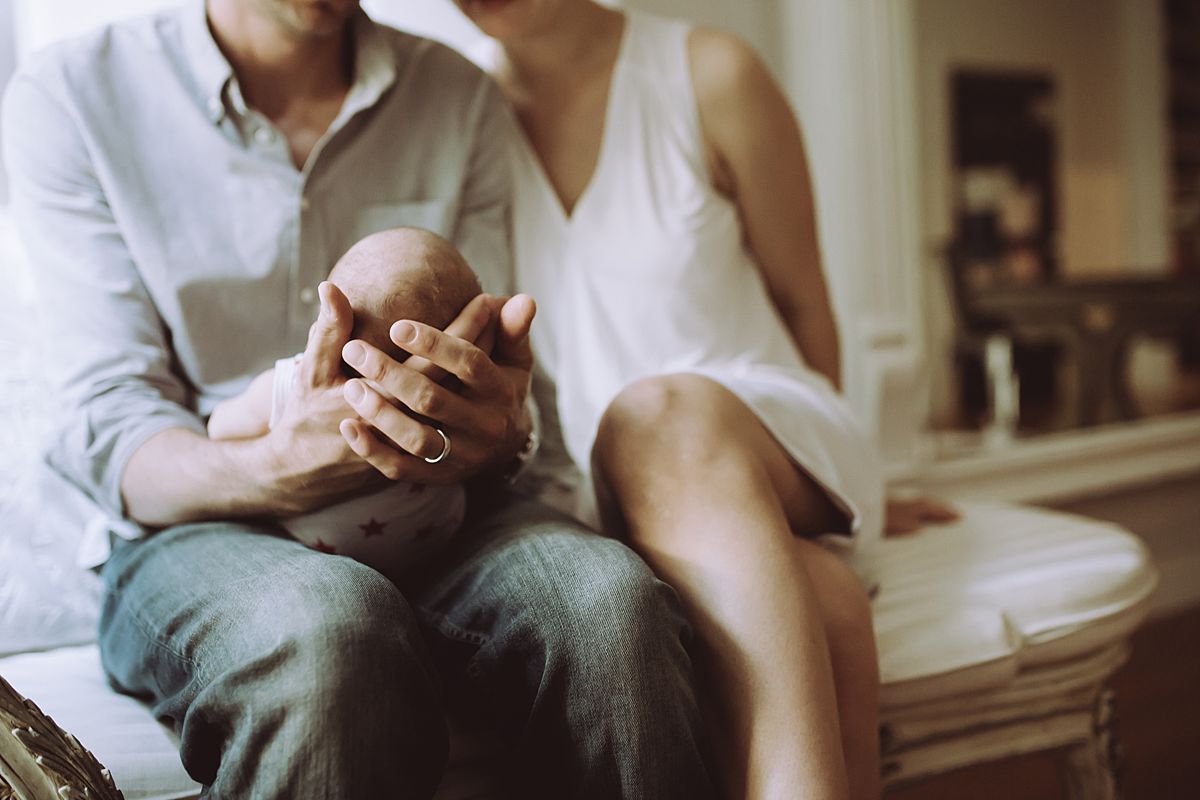 colorful image of mom and dad holding baby girl on family couch. image by nyc family and newborn photographer krystil mcdowall