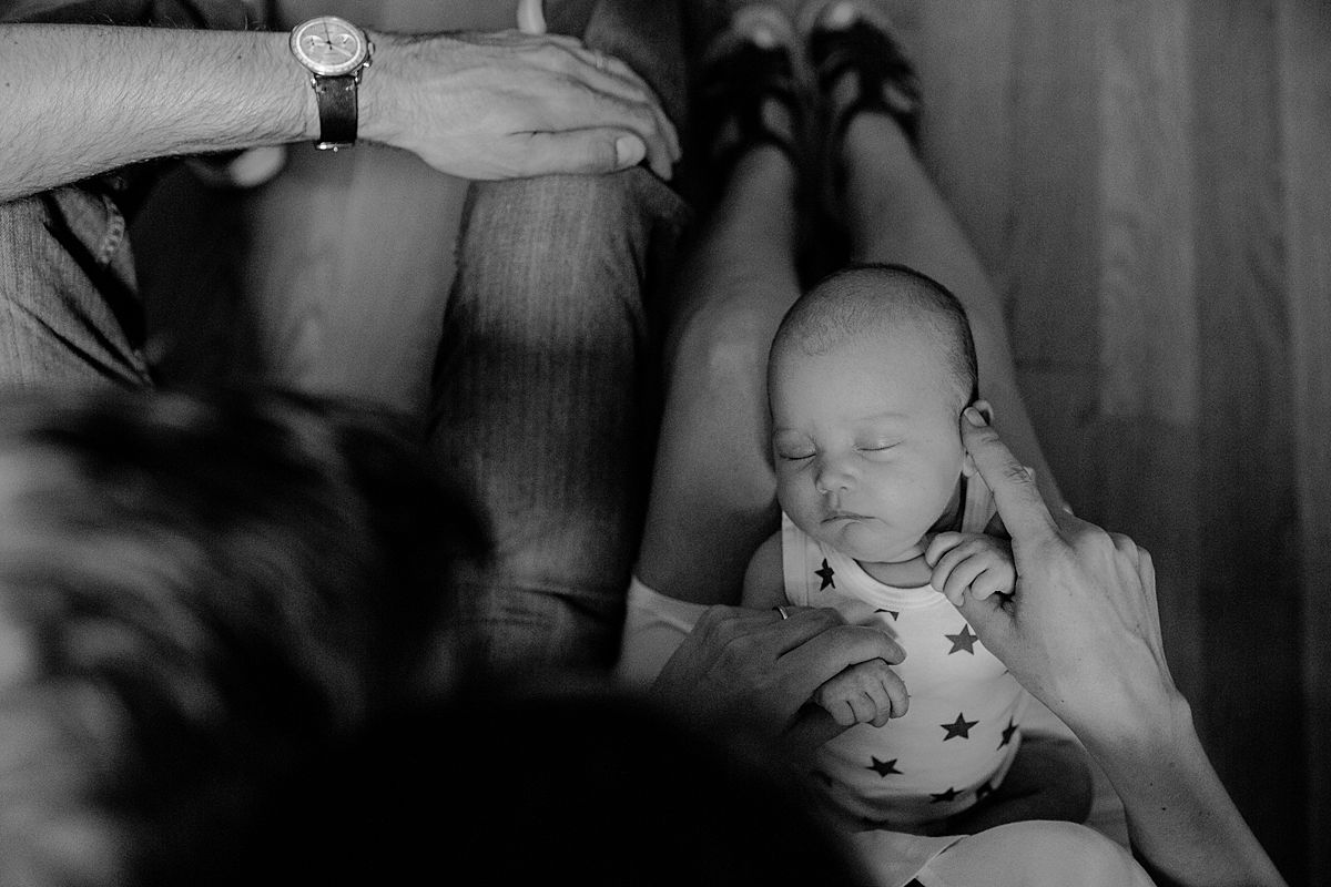 mom caresses newborn girl as she sleeps quietly on mom's lap. image taken in harlem new york by nyc family and newborn photographer krystil mcdowall