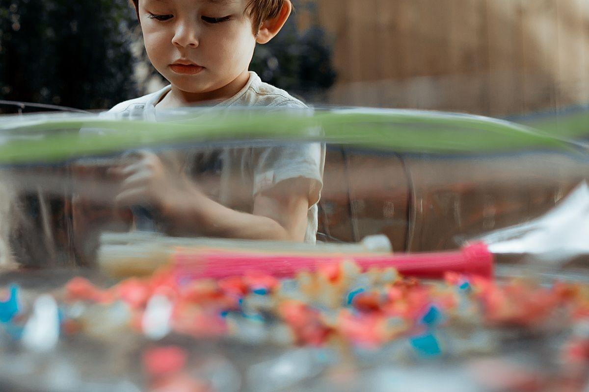 toddler plays with water balloons in backyard during documentary session with krystil mcdowall