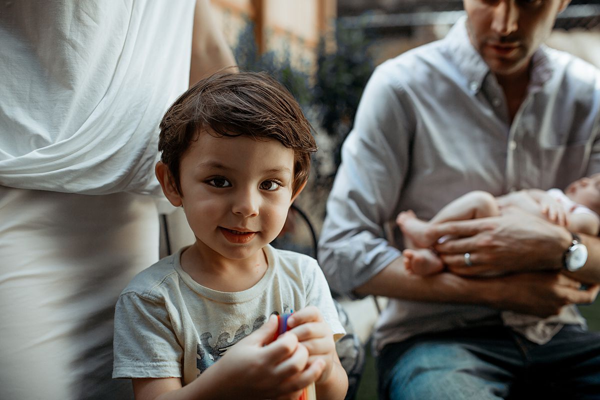 boy playing with water balloons in backyard chair. photo by nyc family and newborn photographer krystil mcdowall photography