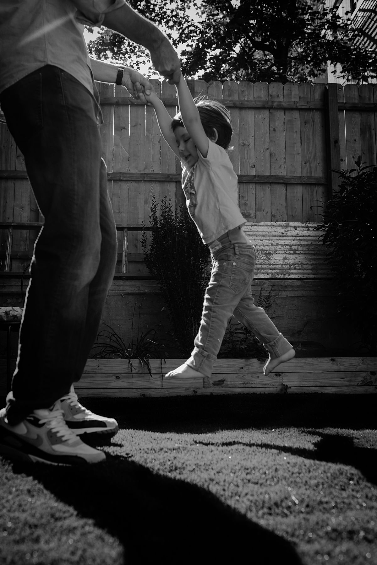 dad swinging son around outside in backyard during fun filled family lifestyle session with krystil mcdowall photography