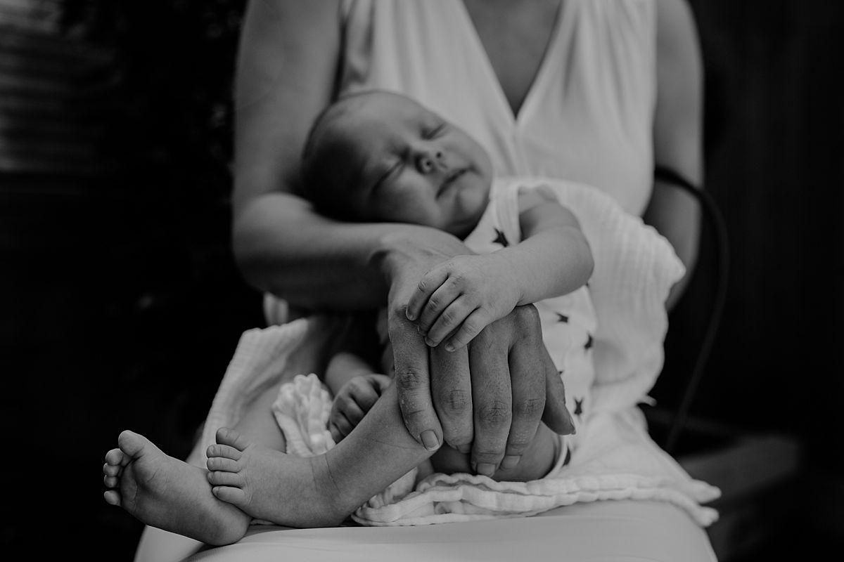 close up newborn baby girl lying across mom's lap outside during family lifestyle session in nyc
