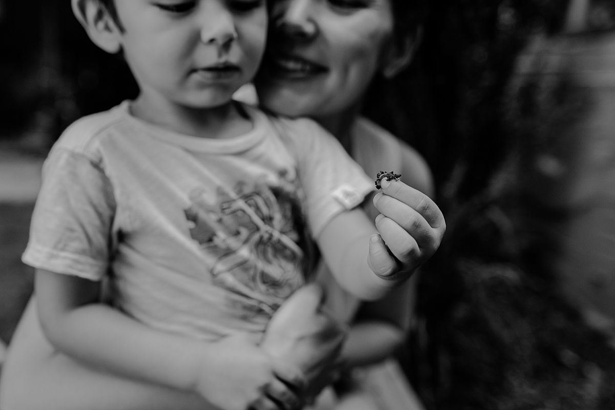 black and white image of mom and son looking at garden bugs. photo by nyc family and newborn photographer krystil mcdowall